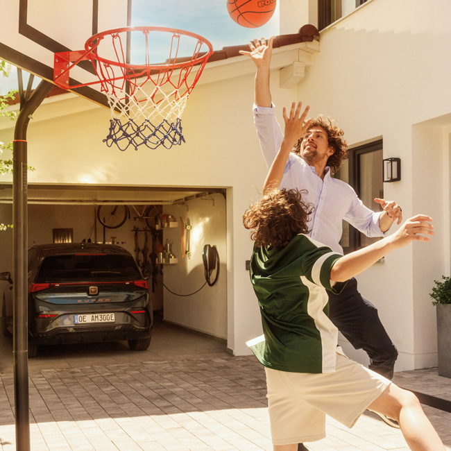 Vater und Sohn spielen vor der Garage Basketball