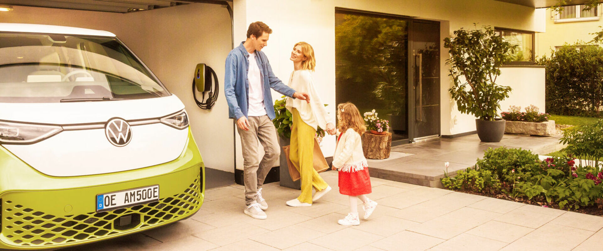 Familie vor einer Garage mit einem E-Auto und einer Wallbox