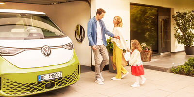 Familie vor einer Garage mit einem E-Auto und einer Wallbox