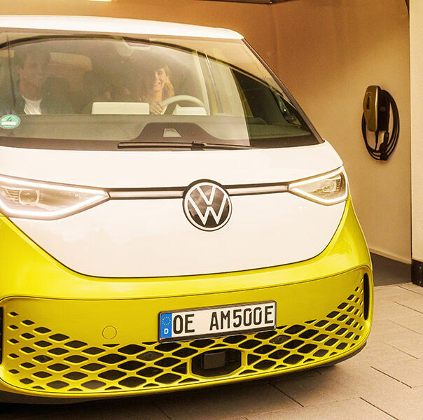 Familie fährt mit gelben E-Auto aus der Garage, daneben hängt eine AMTRON 4You 500 Wallbox in gelb.