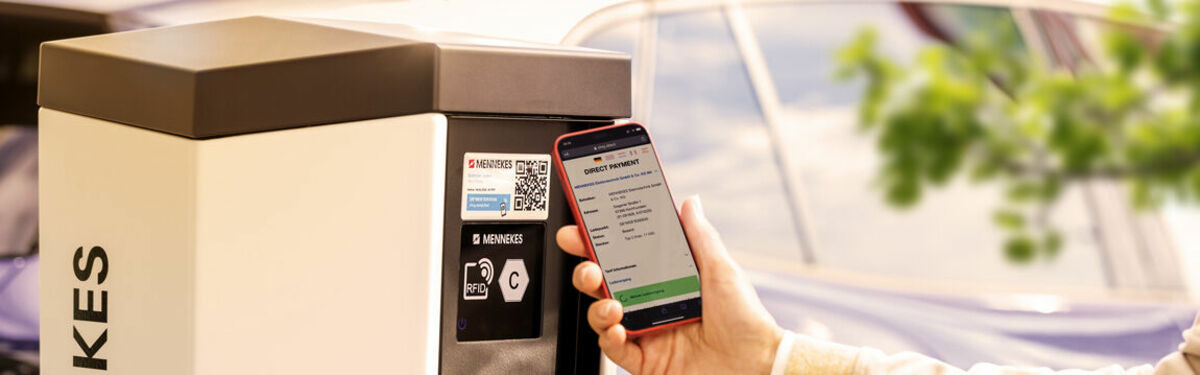 Person scannt an einer Ladesäule den QR-Code mit dem Smartphone